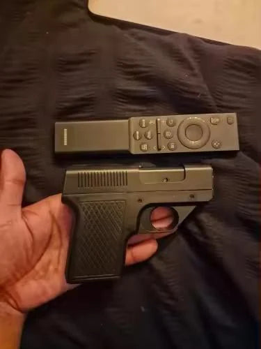 Black Puff-Shot torch lighter held in one hand next to a TV remote for size